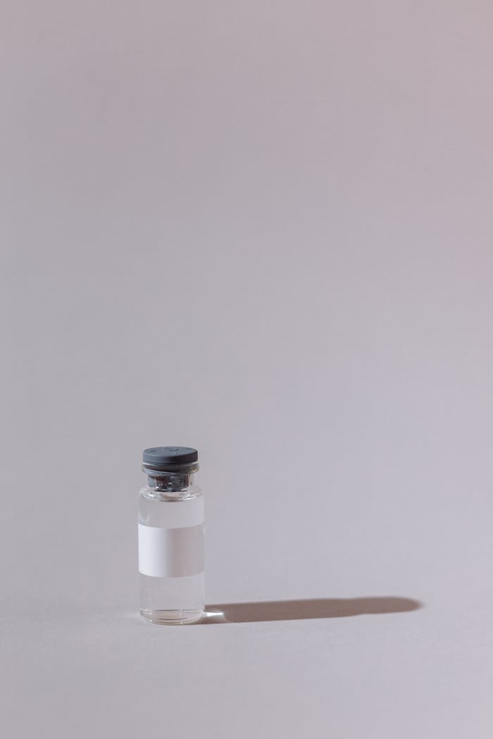 A single glass vial with a cork stopper against a gray backdrop, casting a shadow.